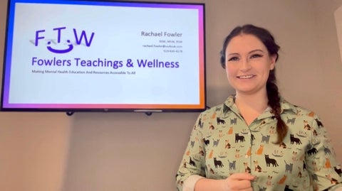 Rachael standing in front of a powerpoint on a screen that has her company name and logo: Fowlers Teachings and Wellness. 