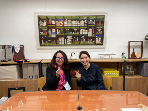 Wendy with one other person at a table. They are smiling at the camera. 