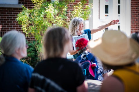 Angled behind the tour group, Juanita is pointing to her left and speaking during a tour