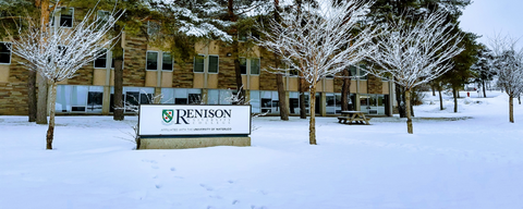 Renison entrance sign with snow on the ground and in trees. 