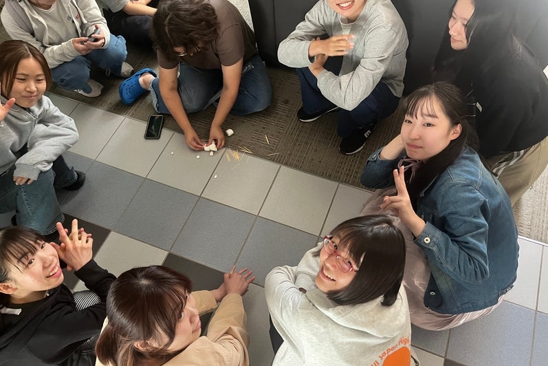 Group of students sitting on the floor, looking up and smiling