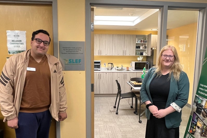Two people standing outside of a kitchenette area