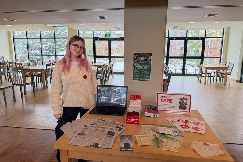 Student next to a booth inside a cafeteria area