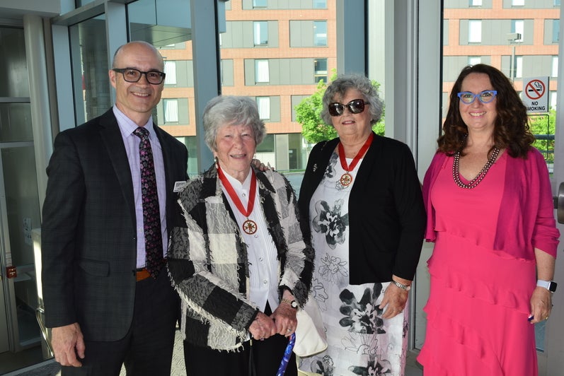 Four people standing in a row in the Renison Atrium