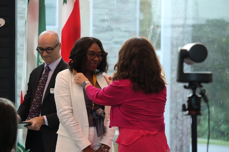 Woman stands in centre receiving an award. 