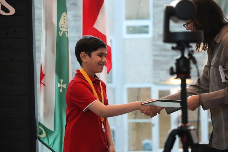 Boy in red shirt receives award. 