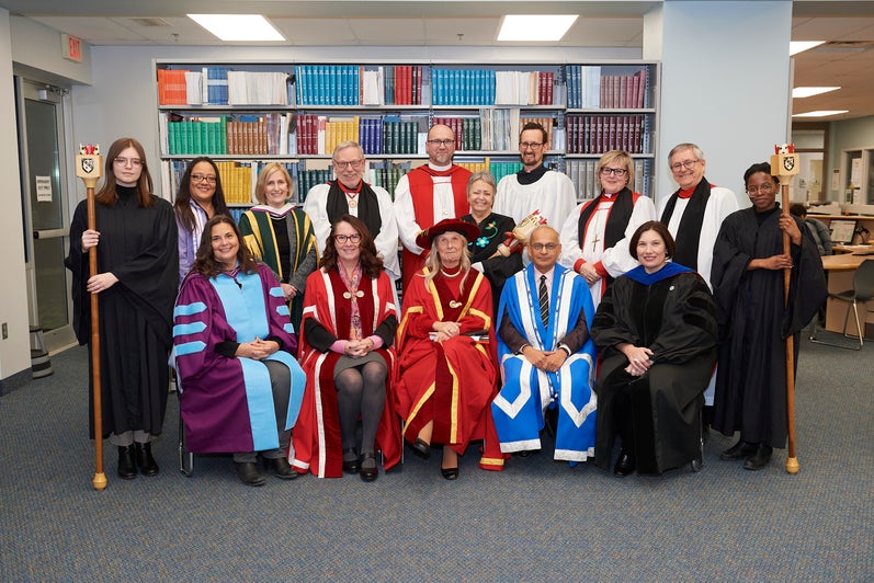 Group shot of all of the people involved in the ceremony, arranged into rows in front of a bookshelf in Renison's library. 