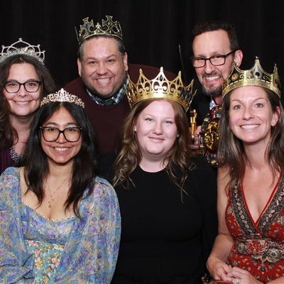 Group of people at an event wearing crowns and smiling. 