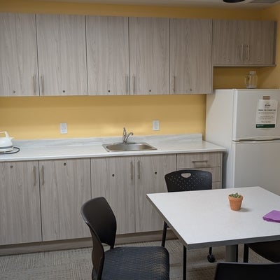 A basic kitchen with a counter, fridge, and a table with chairs. 