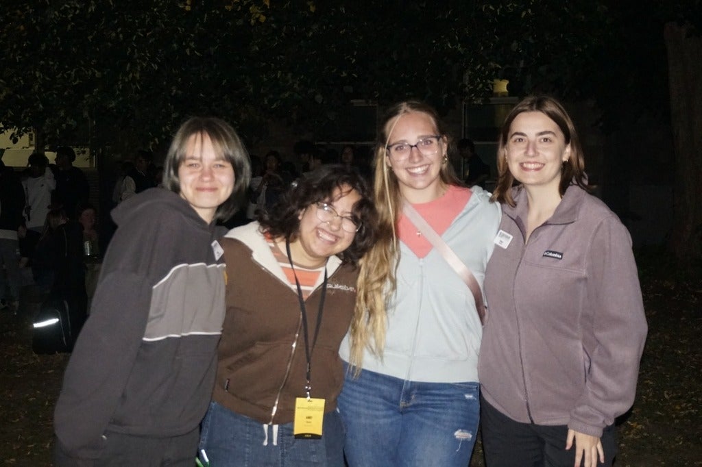 Four students standing together smiling at the camera. 