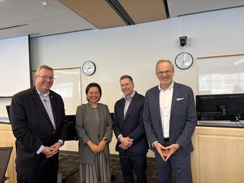 Four people standing in a row smiling at the camera. 