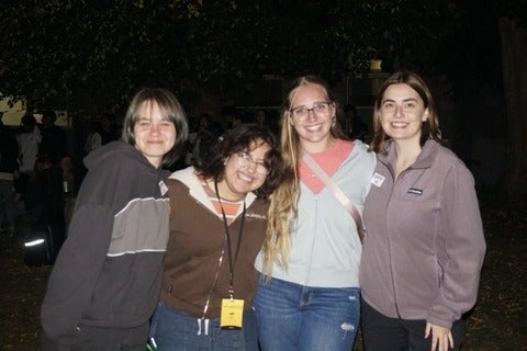 Four students standing together smiling at the camera. 