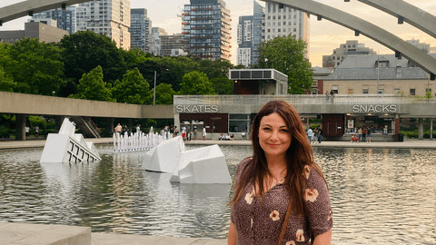 Chelsey Freeman smiling in front of a lake with a bridge and tall buildings in the background