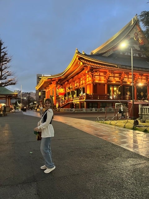 Denise standing near a Japanese-style building during her trip to Japan. 