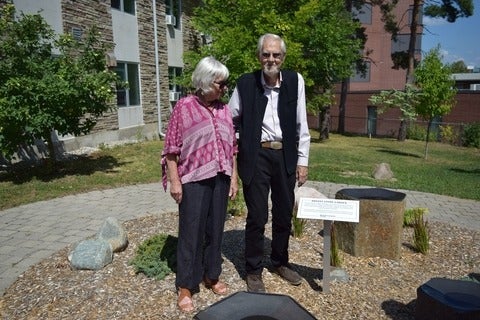 Susan and Darrol Bryant stand in the stone garden beside the newly unveiled plaque.