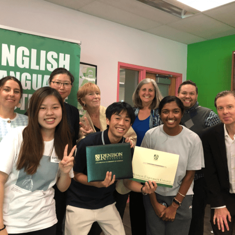 A group of people standing in a classroom at Renison. The person who is in the centre is holding their certificate. All are smiling. 