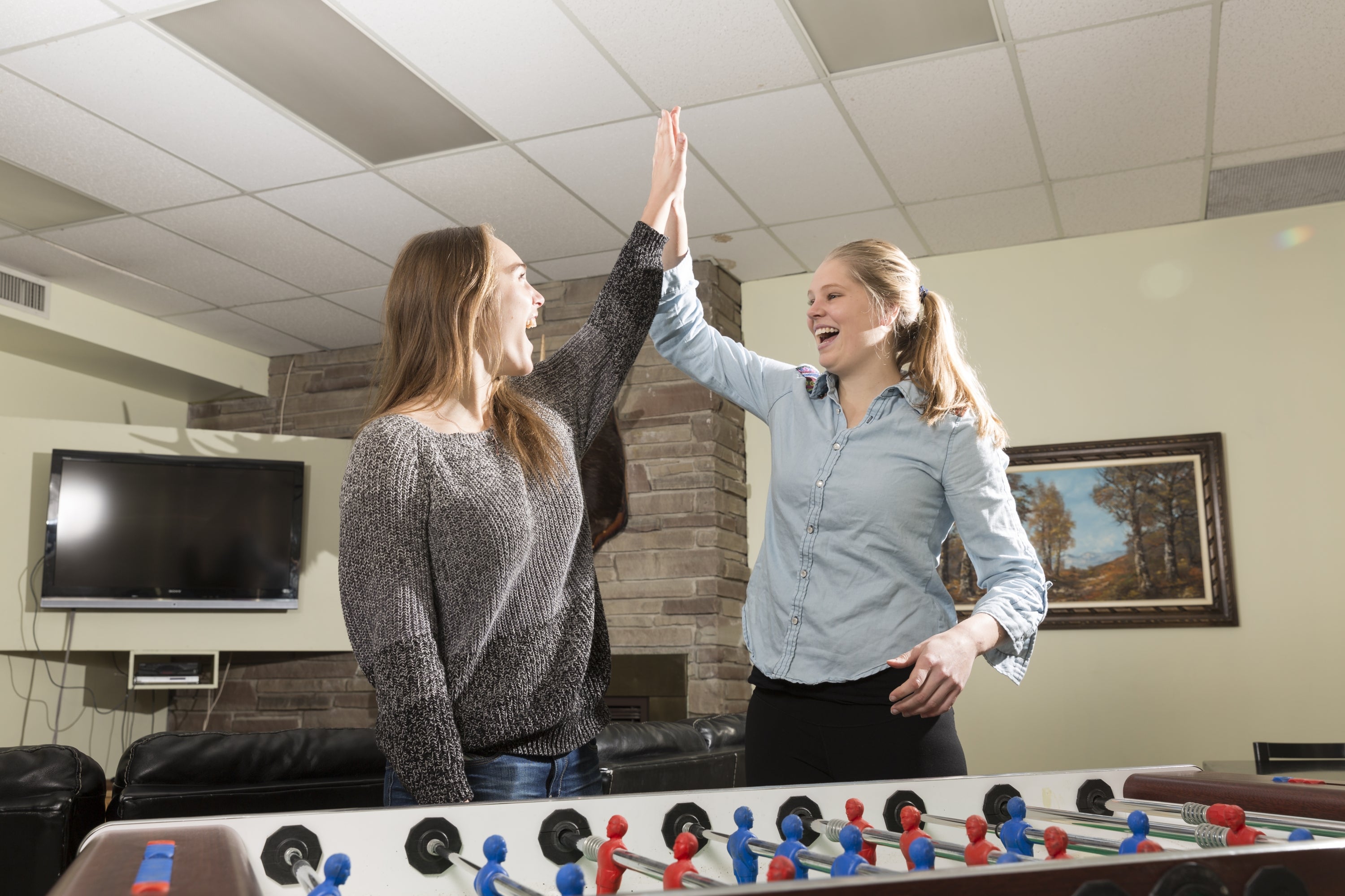 two girls high five over foosball table