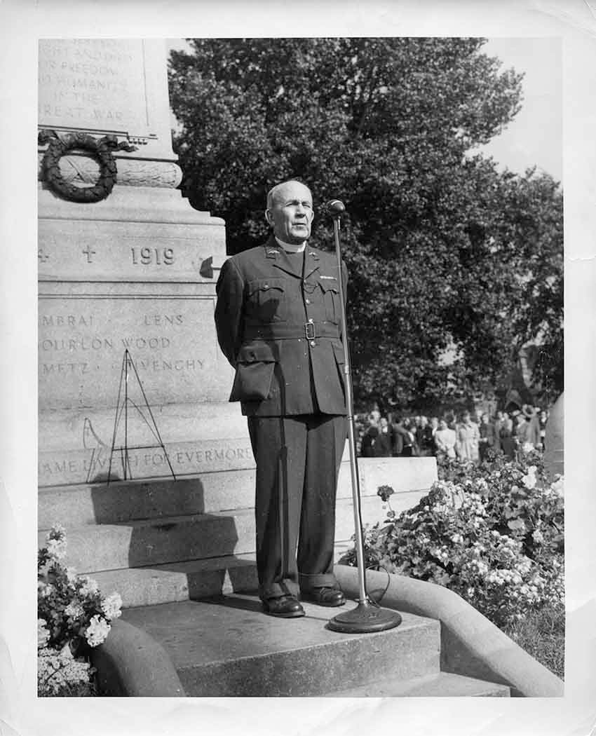 Photograph of Rev. Robert J. Renison in front of the North Bay cenotaph 