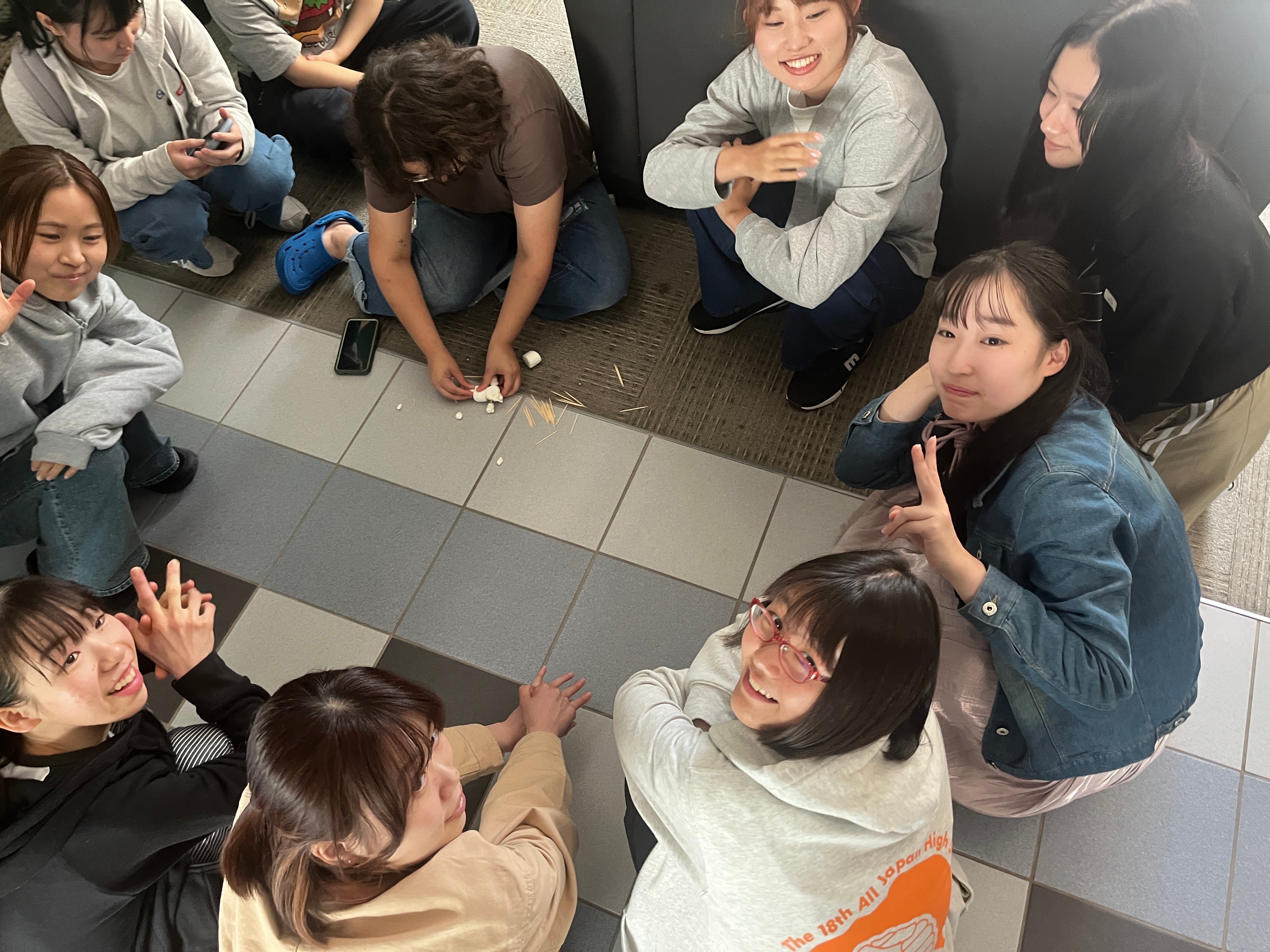 Group of students sitting on the floor, looking up and smiling