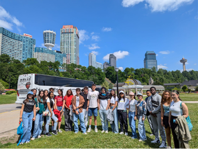 Students standing in a group in front of a bus. 