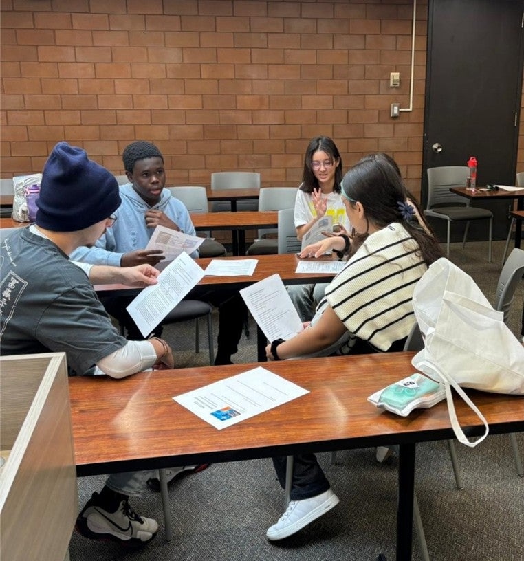 Students sitting at tables working together on a project. 