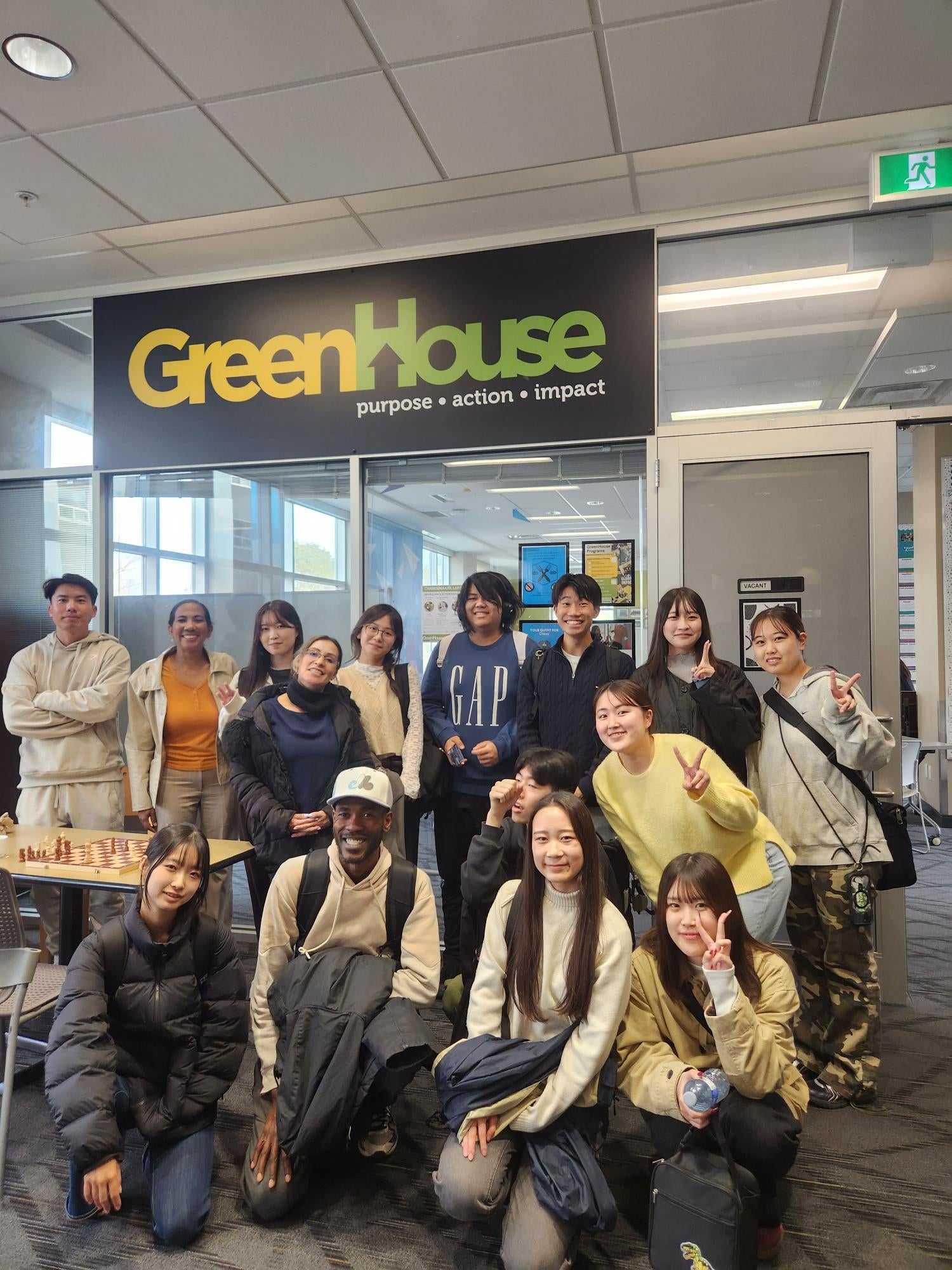A group of students standing in front of the Green House sign at UW. 