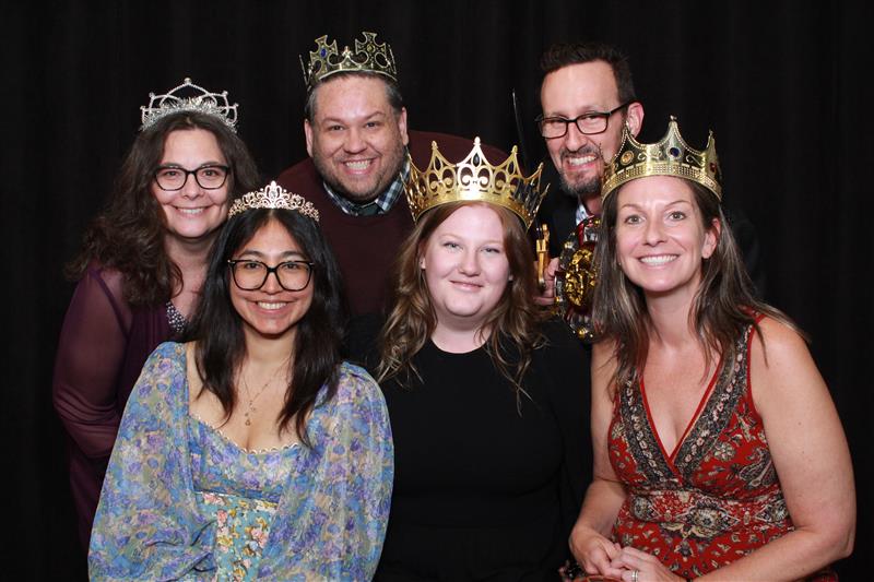 Group of people at an event wearing crowns and smiling. 