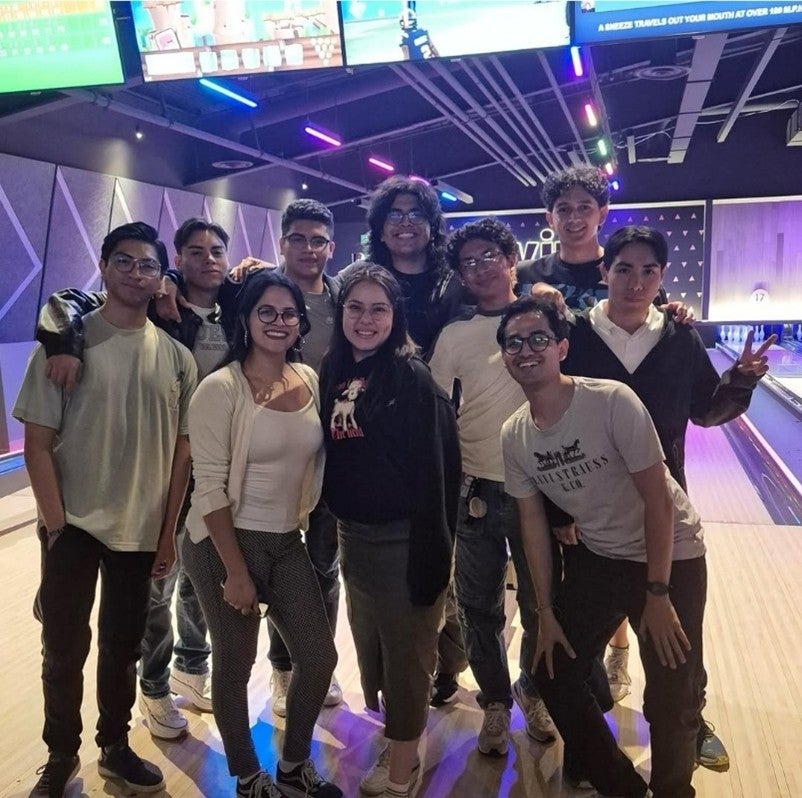A group of students standing in front of bowling lanes. 