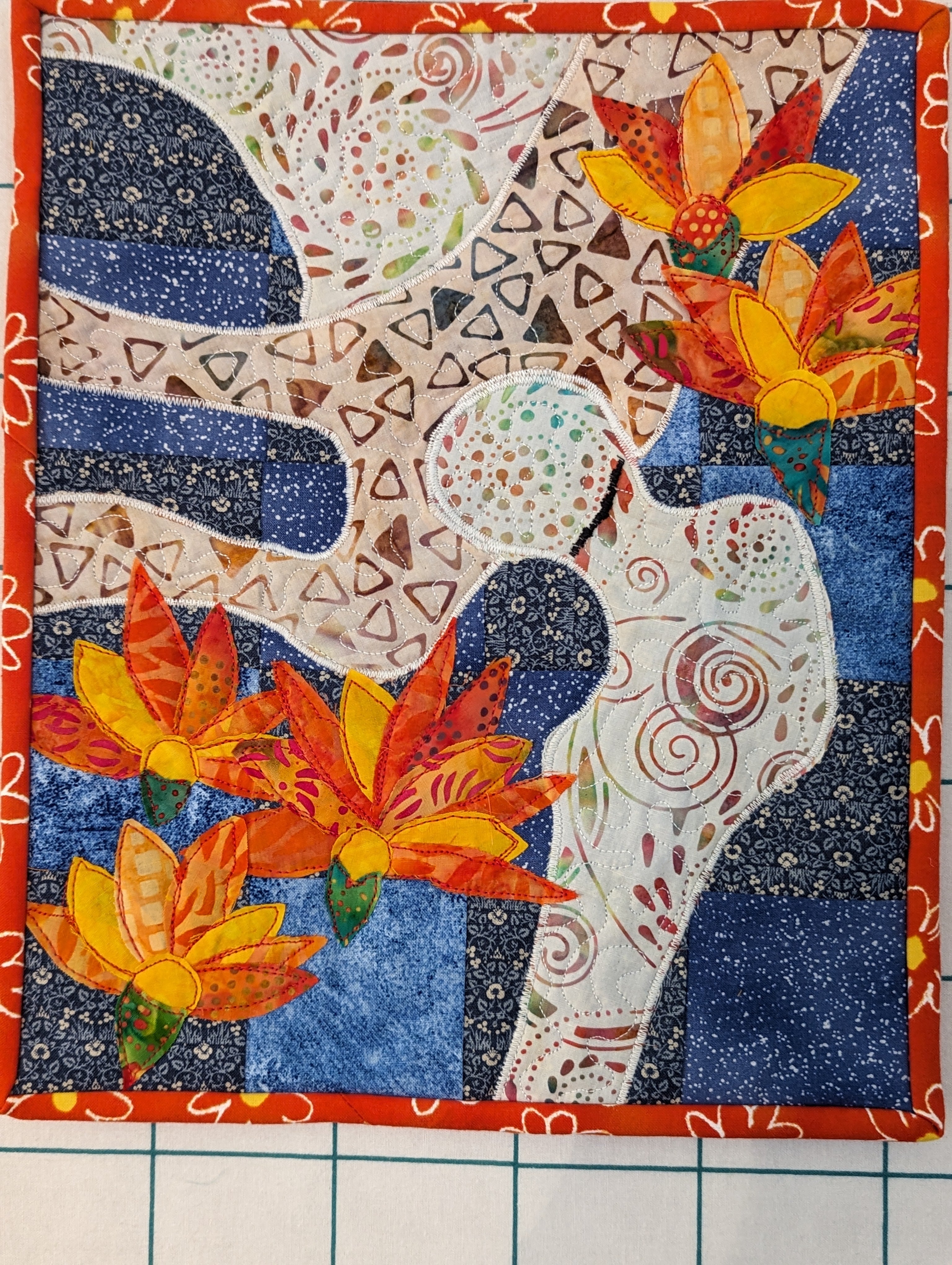 An art quilt showing a hip joint and flowers. 