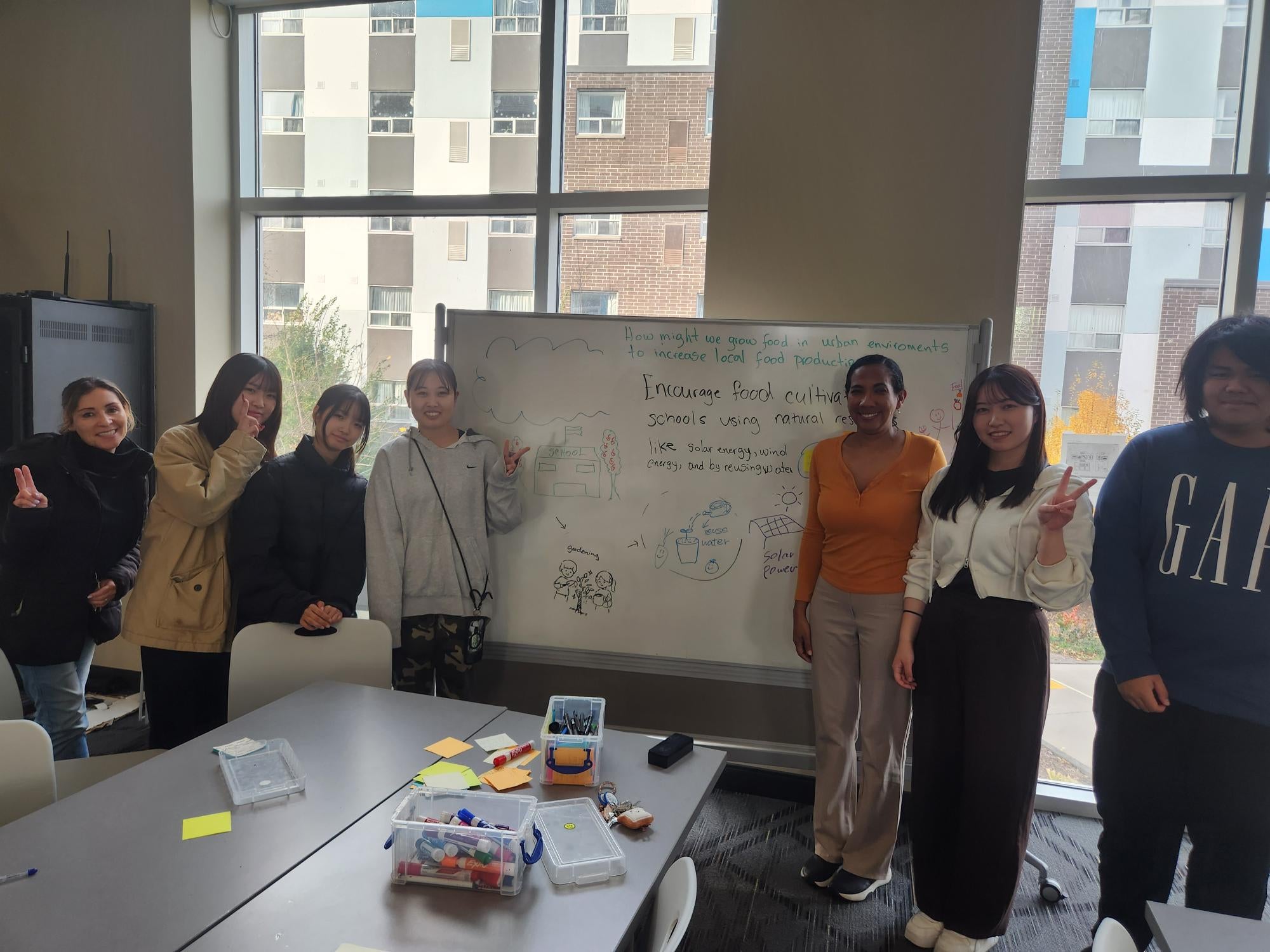 Students standing beside a whiteboard with notes on it about food cultivation. 