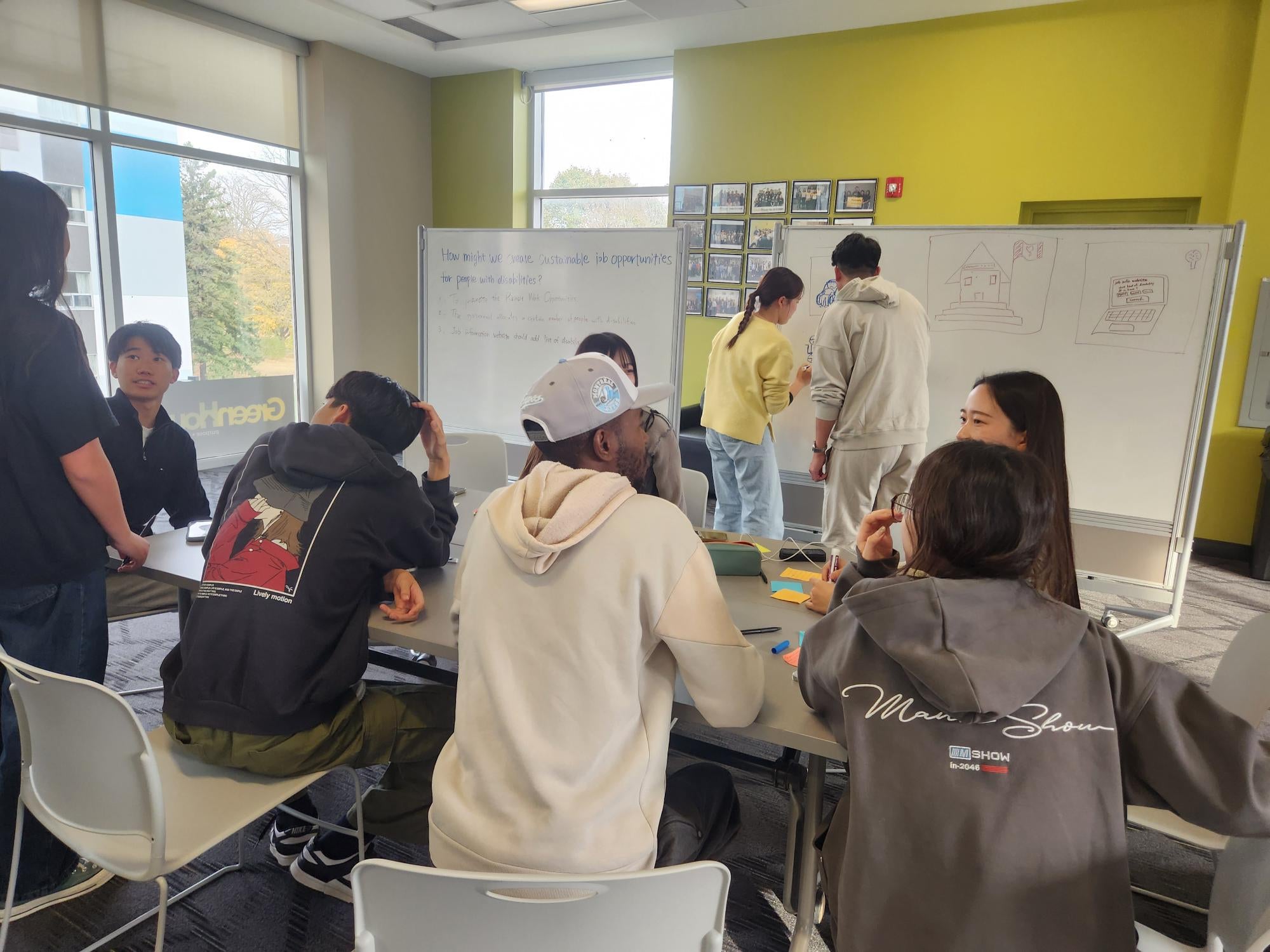 Students working at tables and writing on whiteboards. 