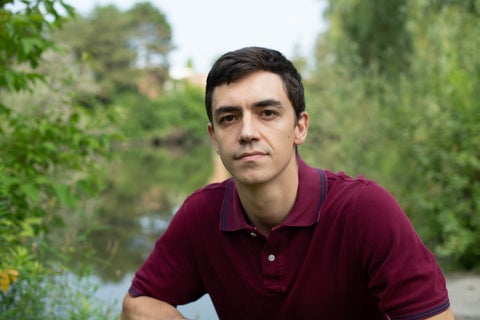 Man in red shirt in front of lake