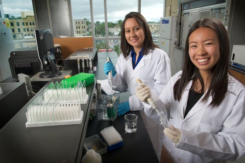 Two people in lab coats siting at a lab table