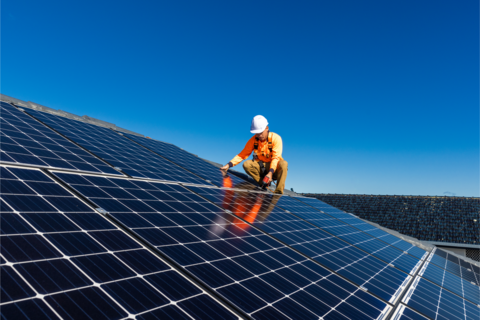 Man installing solar panels on a slanted roof