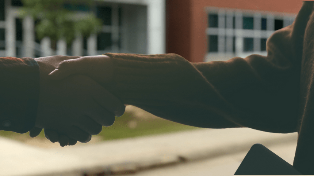 Two people shaking hands in front of a building