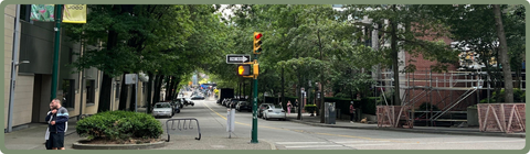 A tree-lined street in downtown Vancouver providing shade to pedestrians.