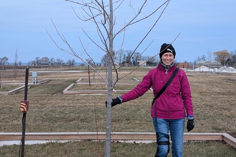 Julie Messier standing beside a tree at the outdoor TreeCulture Park at Vineland Research & Innovation Centre.
