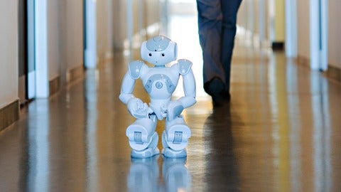 NAO robot crouching in a hallway