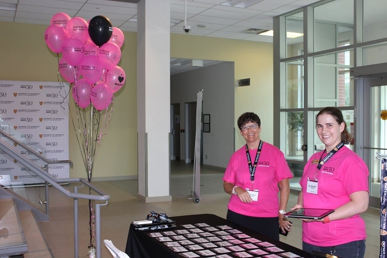 women at registration table with pink balloons