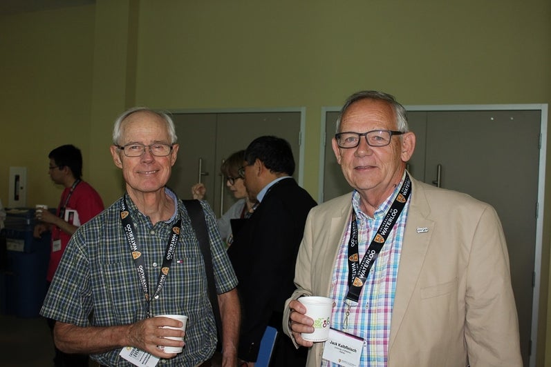 two men with plaid shirts and UWaterloo lanyards enjoying coffee