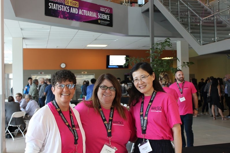 three women smiling with pink shirts and UWaterloo lanyards