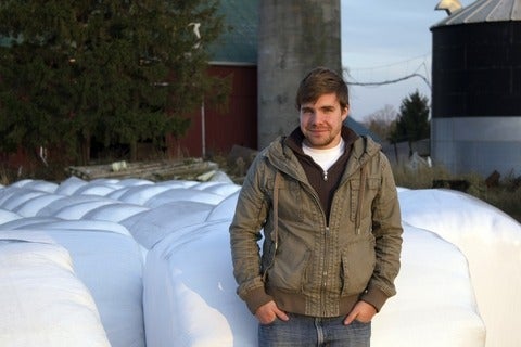 Shane Hedderson leaning against haybales