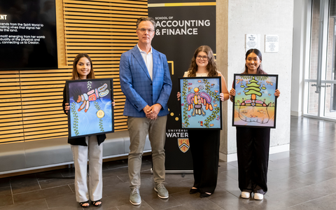 Blake Phillips and three students holding prints of the Indigenous mural he commissioned