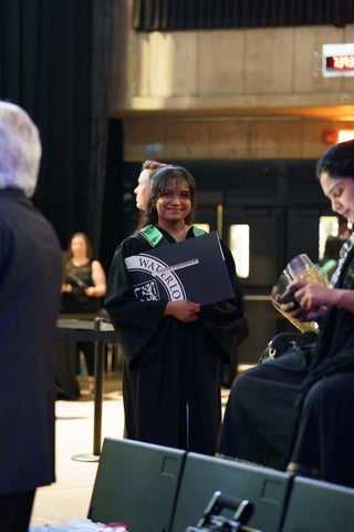 Yammunna holding her diploma at her convocation