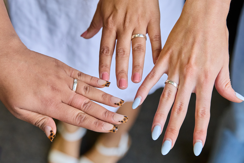 A closeup of three SFM graduate hands wearing their class rings