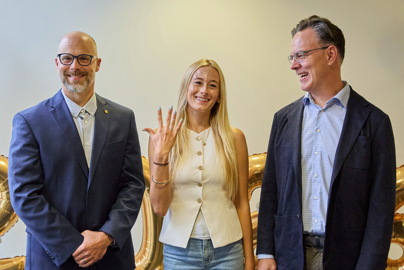 Blake Phillips and Michael wood pose for a photo with an SFM graduate who is showing off her class ring.