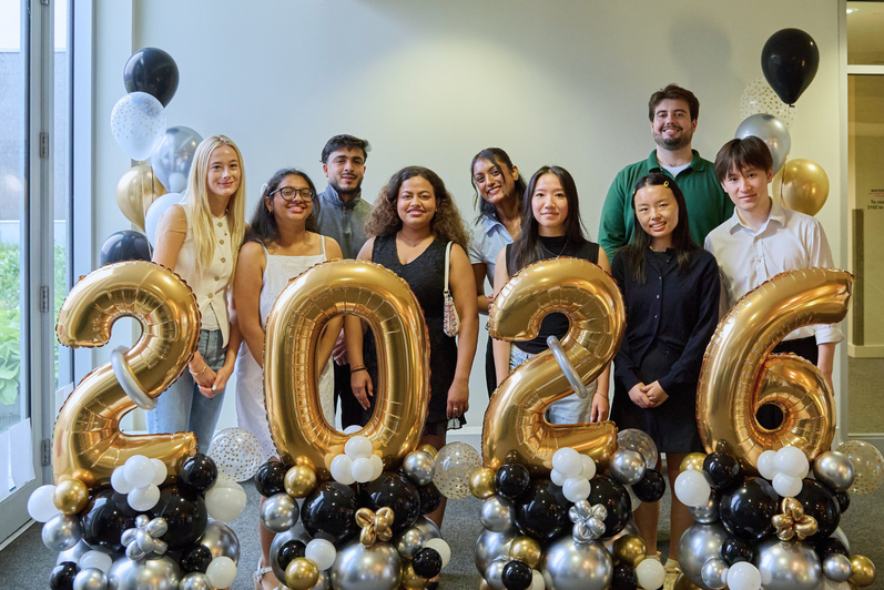 The first cohort of SFM graduates pose with "2026" balloons.