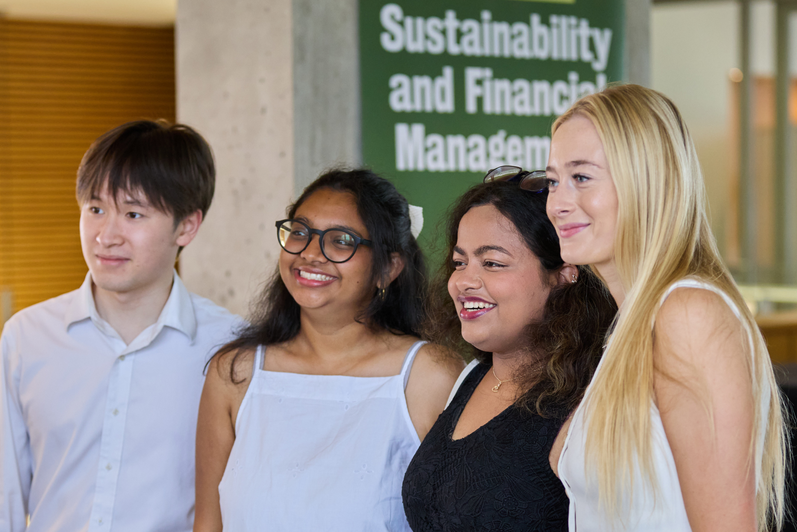 Four SFM graduates pose for a photo together.