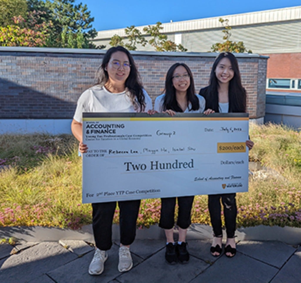 Image of Rebecca, Isabel and Maggie holding a cheque. 