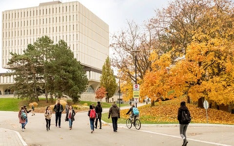 Students walking in front of Dana Porter Library during the fall season